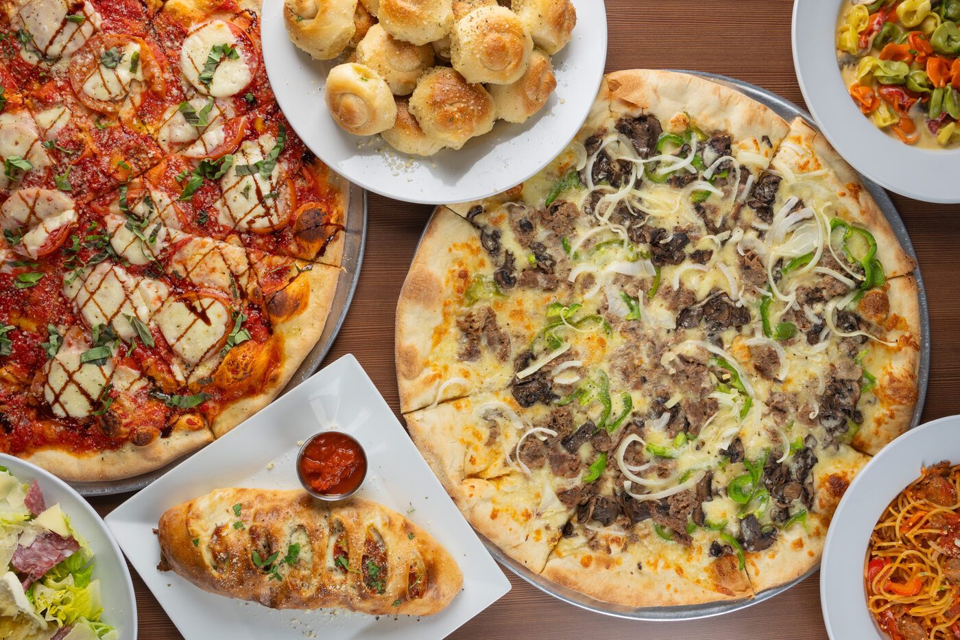 Family-style spread of pizza, garlic knots and pasta
