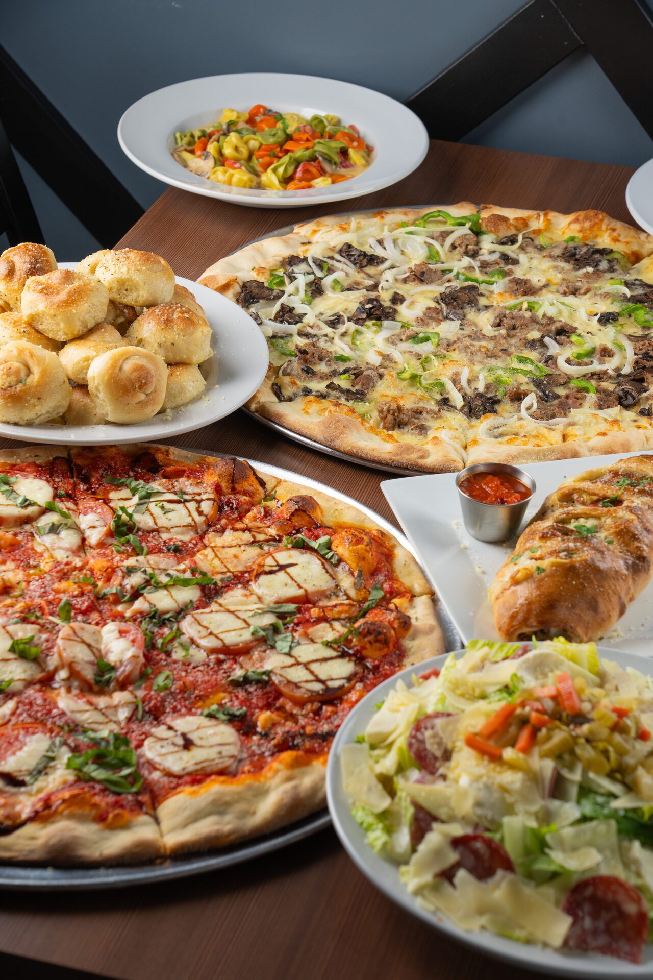 Family-style spread of pizza, garlic knots and pasta